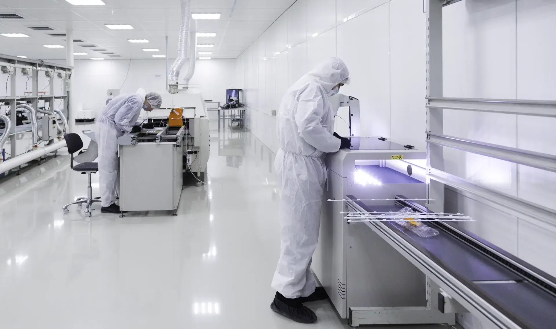 Techniciens en combinaison blanche travaillant dans une salle blanche ISO, conception et suivi par Arkeom